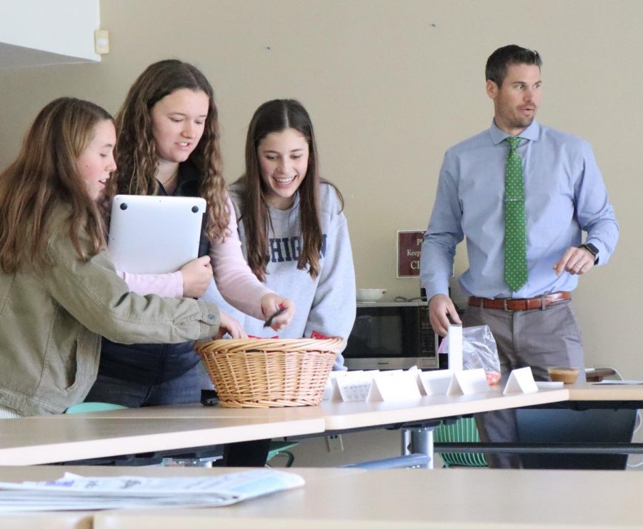 Juniors Anya Bodine-McCoy, Caitlin Fitzgerald, and sophomore Samantha Parr take candy given out before the meeting, as Assistant Principal Nate Severin gets his own snack. 