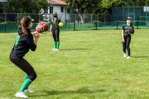 Sofia Barker throws a softball to her teammates while Jasmin Desruisseau awaits her turn during passing drills.