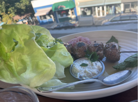 A plate of the Lamb Meatballs with Tzatziki, lettuce and pickled onions, on a table overlooking downtown San Anselmo.