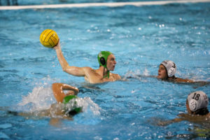 Senior Cole Wooster holds the ball out of the water while looking to pass it to a teammate.
