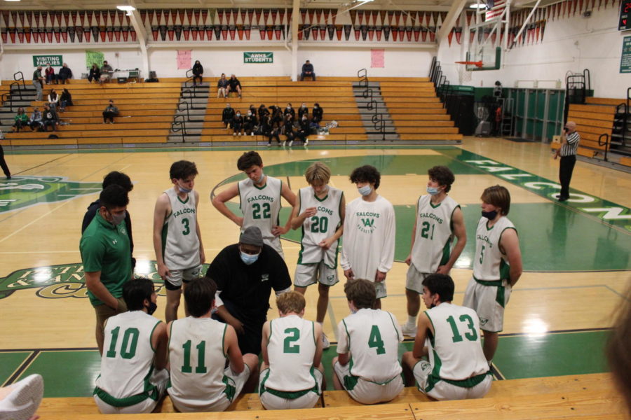 The AWHS boys junior varsity basketball team surrounds Coach Weldon Miller, giving instructions during a timeout.