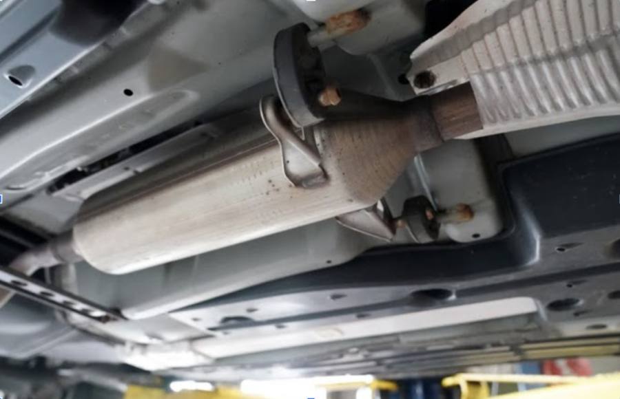 A catalytic converter, recently subject to being stolen, on the underside of a car, used to regulate harmful emissions. 