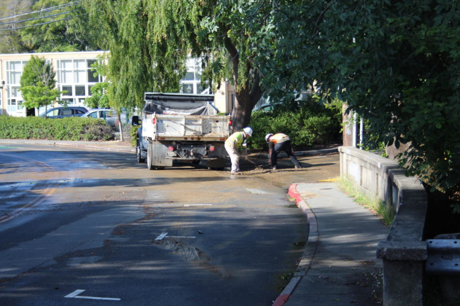 Two Marin Municipal Water District workers dig up mud at the AWHS Saunders parking lot entrance.