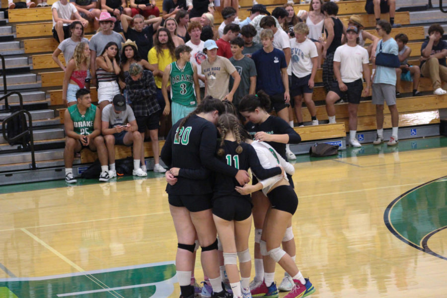 Varsity+girls+go+into+a+team+huddle+to+discuss+their+next+move.+The+Falcons+student+section+is+pictured+in+the+back.