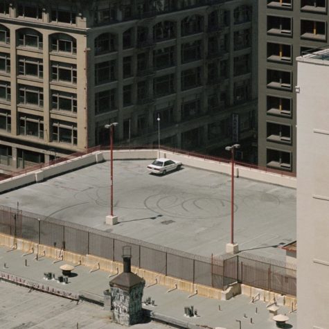 A rooftop car park with a single white car in it.