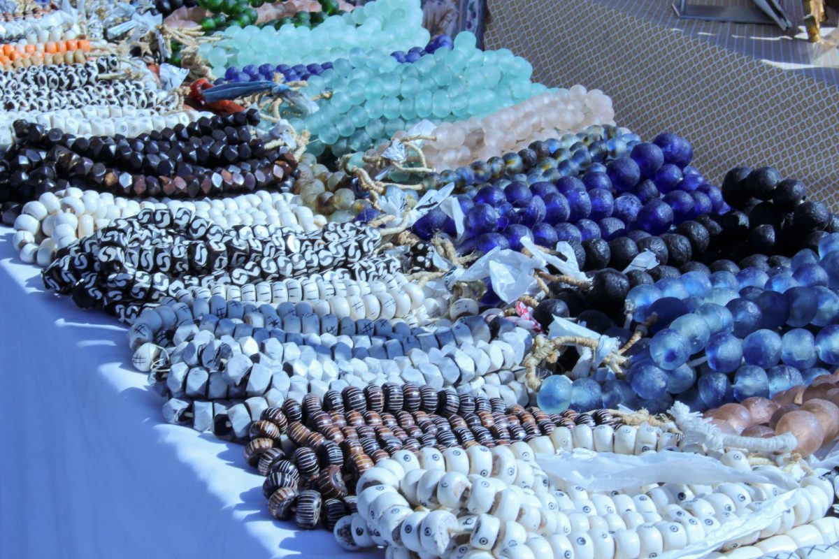 Handmade glass and stone beaded necklaces being showcased at a jewelry stand.