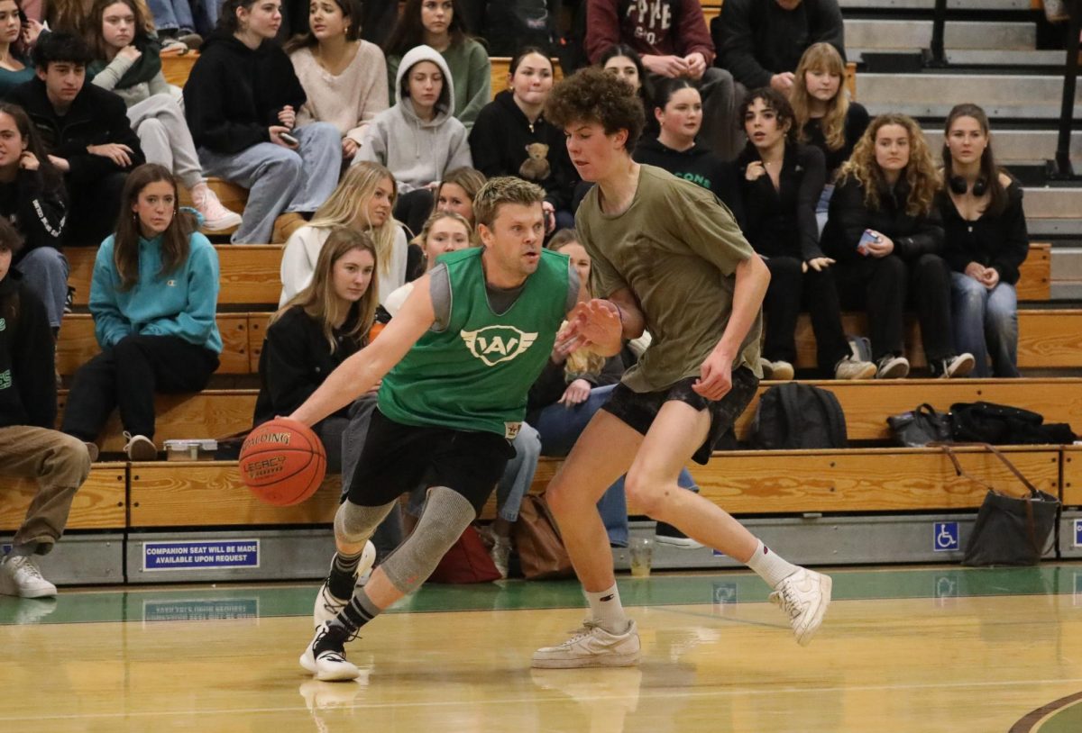 Basketball coach Russel Bauer succeeds in maneuvering past Archie Williams junior Logan Burke during the Staff vs. Student basketball game on Feb. 9. 