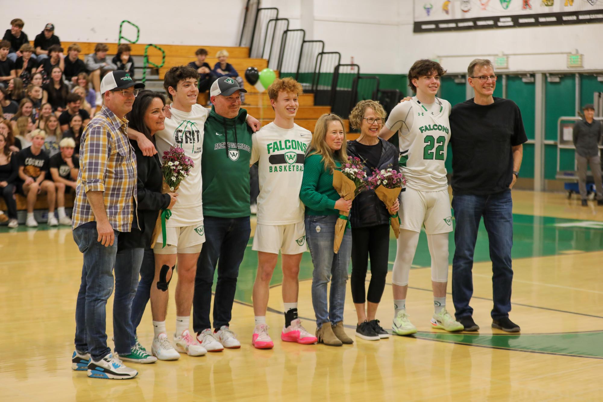 The seniors of the varsity boys basketball team line up for a photo with their parents.