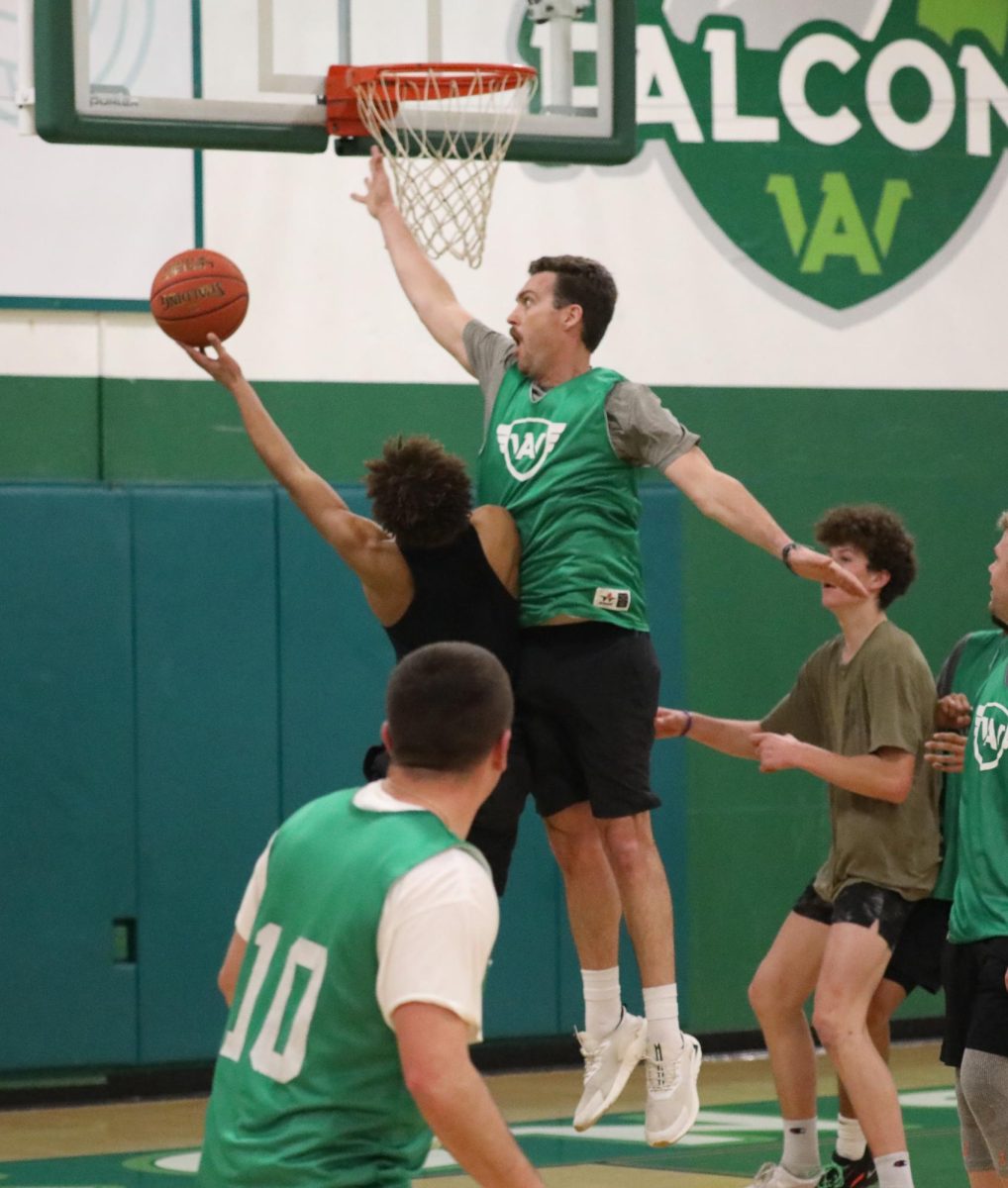 Archie Williams P.E. teacher Tim Parnow jumps to block a shot from sophomore Kai Smith during a Staff vs Student basketball game on Feb. 9.