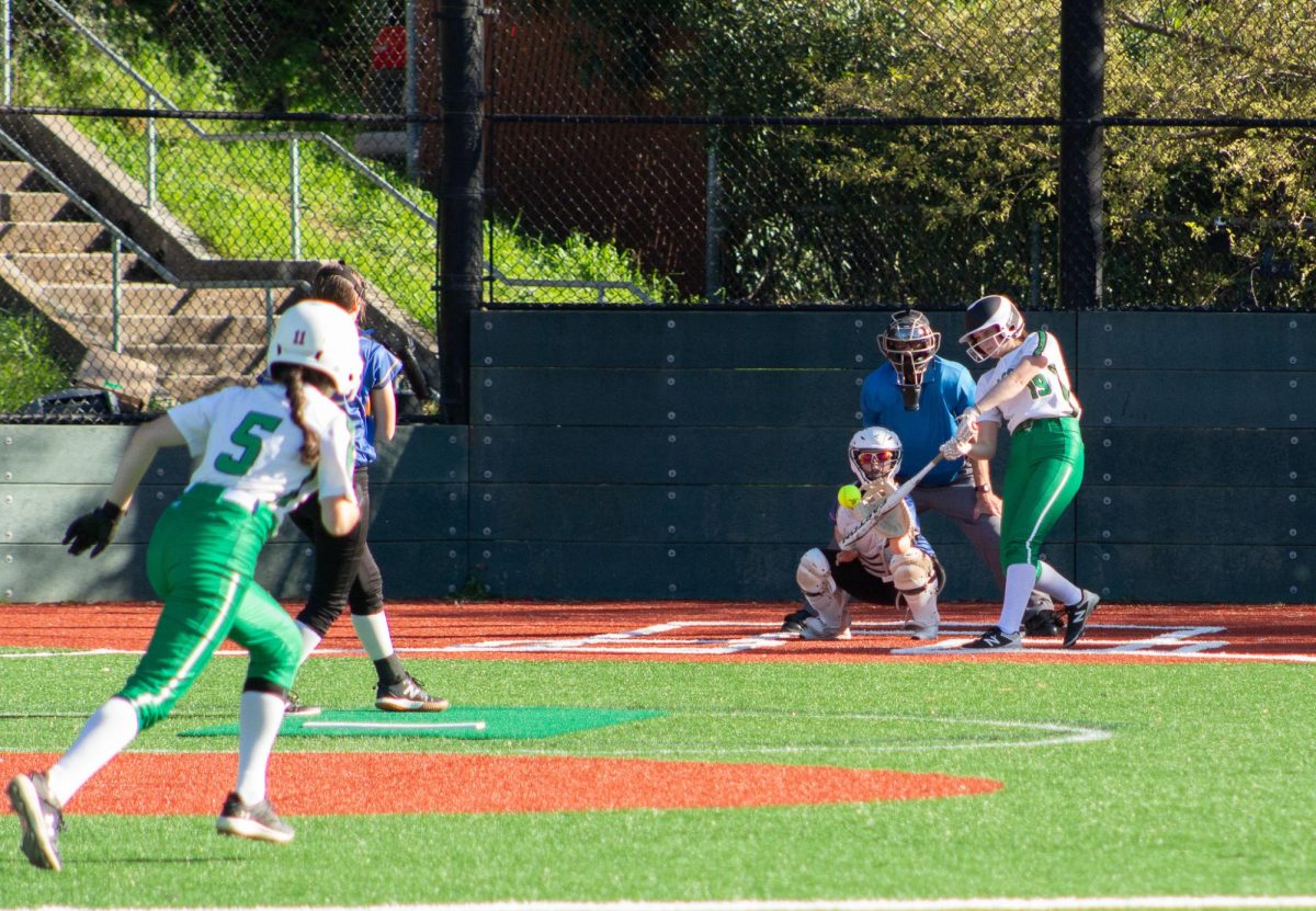 Senior Sarah Conway drives her bat to the ball while freshman Sam Singer steals third base.