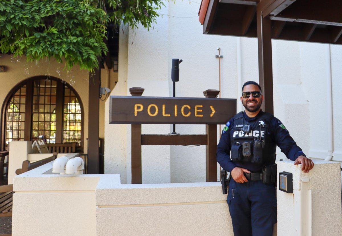 Officer Daniel Novoa poses with the sign leading up to the San Anselmo police station. 