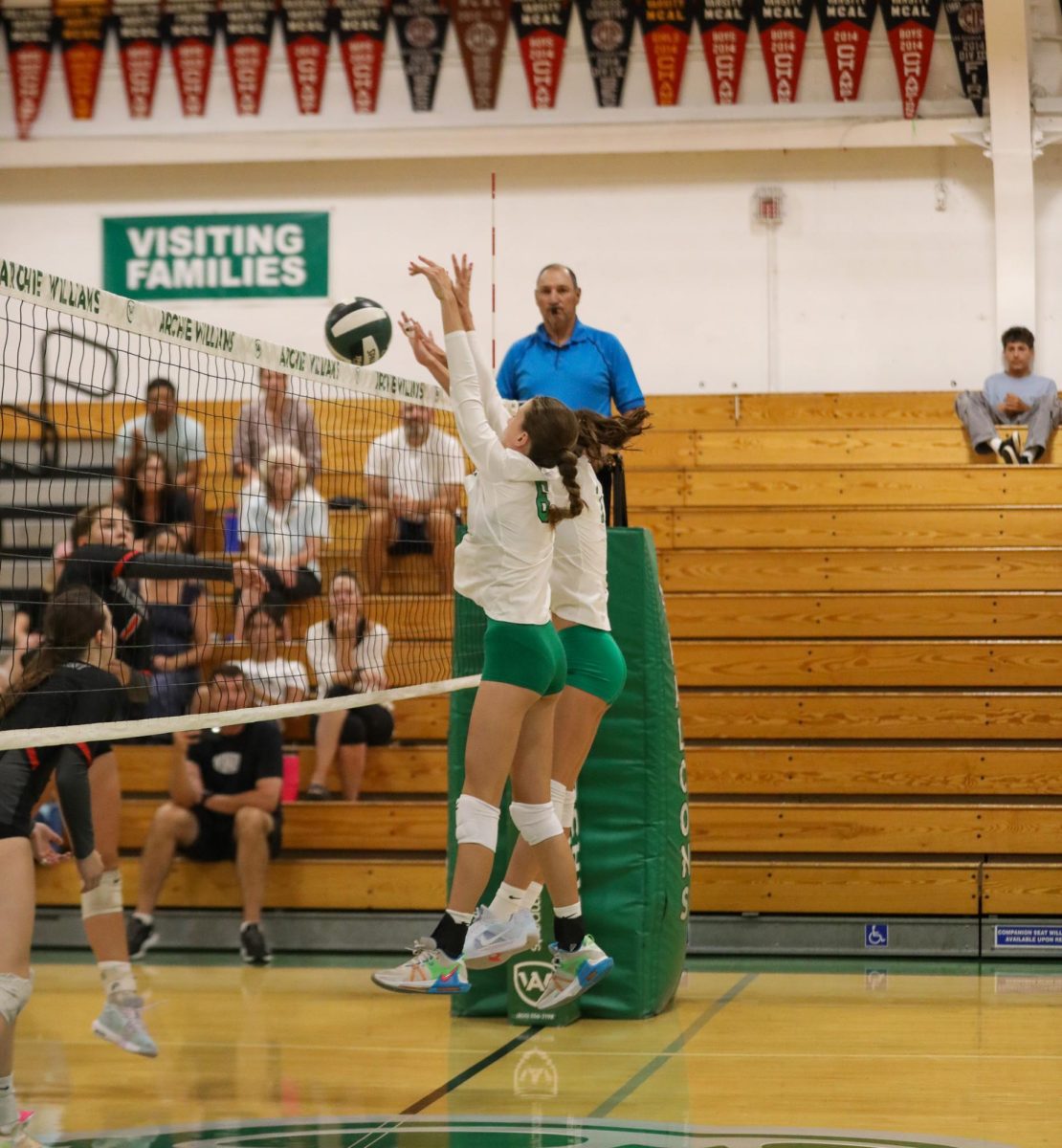 Freshman Ada Nicholas and sophomore Lydia Battaglia block an incoming spike from a Marin Academy Wildcat.