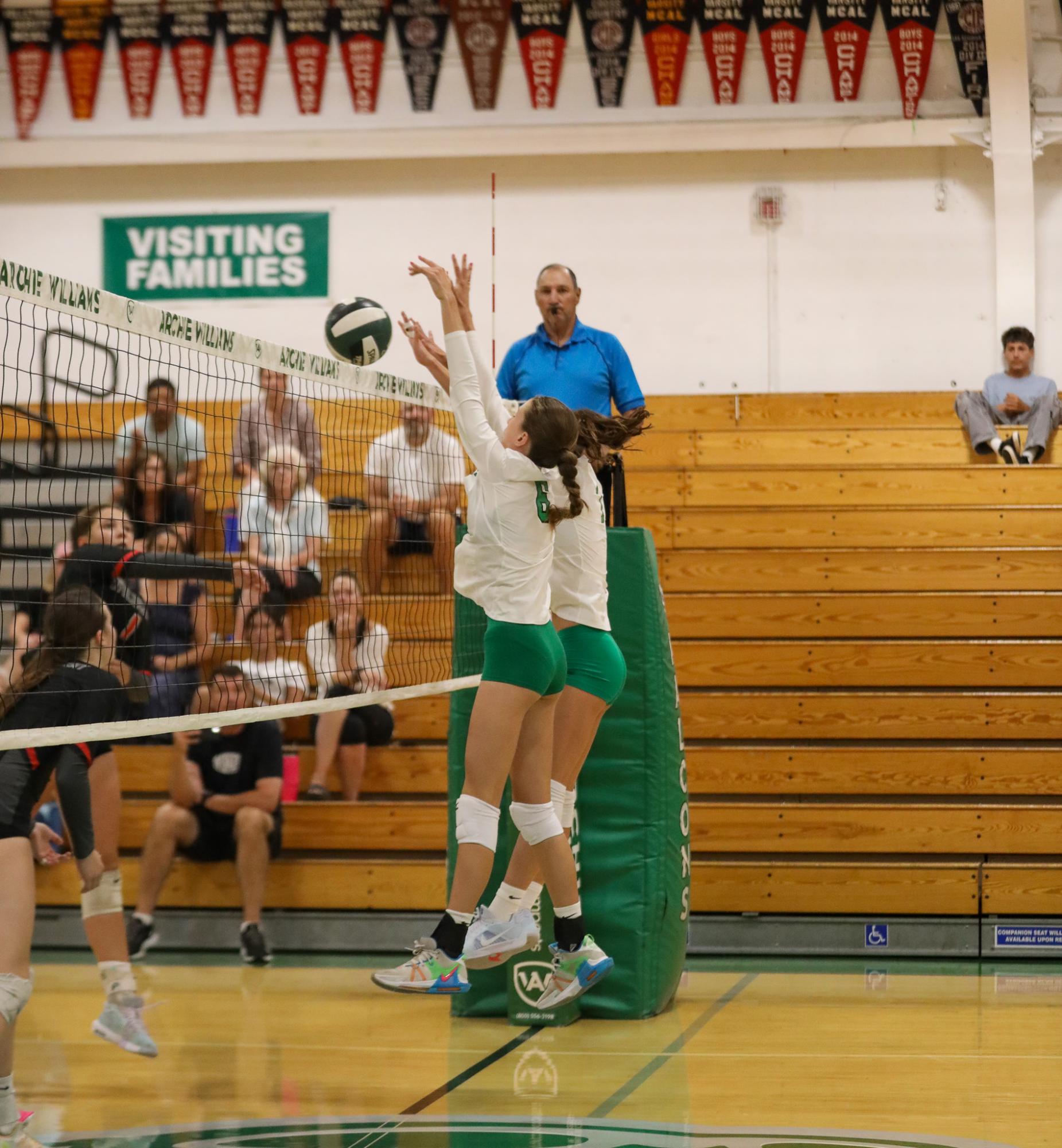 Freshman Ada Nichols and sophomore Lydia Battaglia block an incoming spike from a Marin Academy Wildcat.