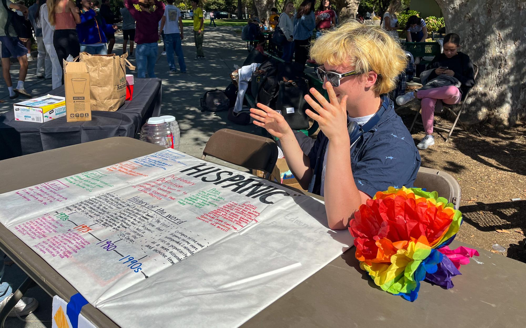 Senior Casey LeFevre-Trigg teaches students about the origin of the word 'hispanic' at a lunchtime booth.