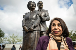 At the opening of the Mendez Tribute Monument Park in Westminster, California, Sylvia Mendez stands proudly beside a statue of her parents, Gonzalo and Felicitas Mendez. (courtesy of Paul Bersebach of NBC News)