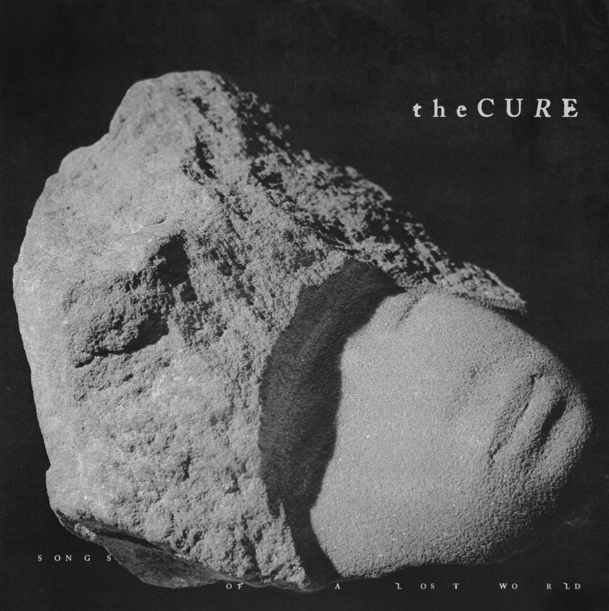 The cover art for The Cure's newest album, Songs of A Lost World, depicts a light gray, misshapen stone contrasted by a dark background.