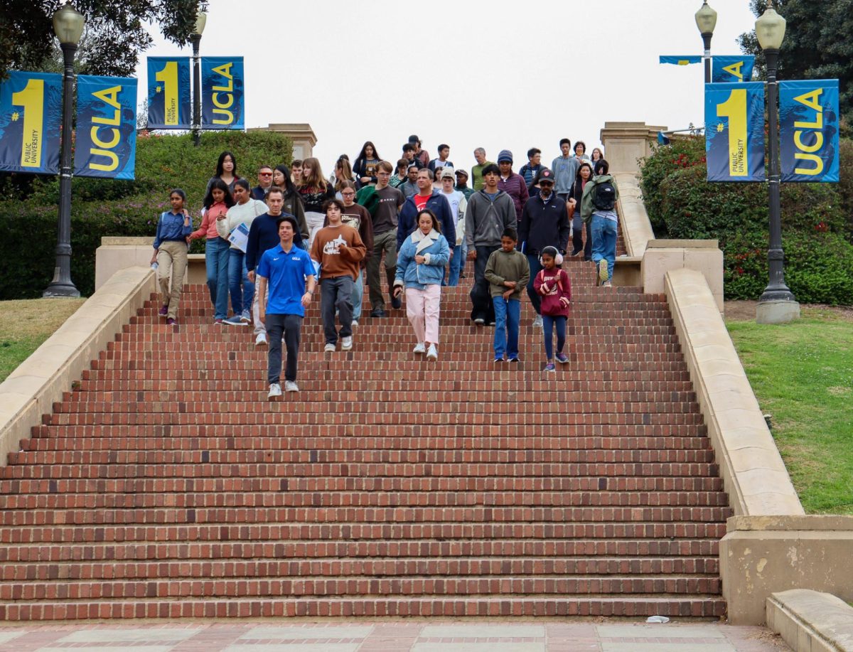 A University of California, Los Angeles tour guide leads a college tour down steps.