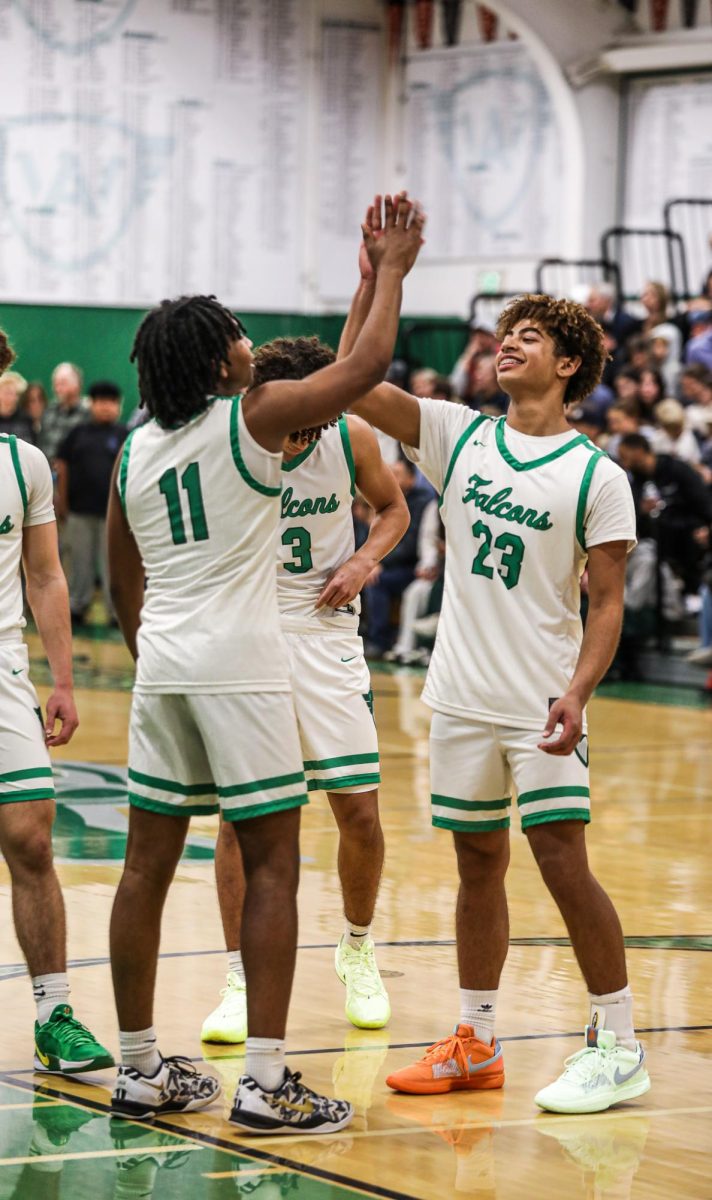 Junior Kai Smith helps junior Ephraim Sohn do his walkout handshake while they announce the starting lineup.