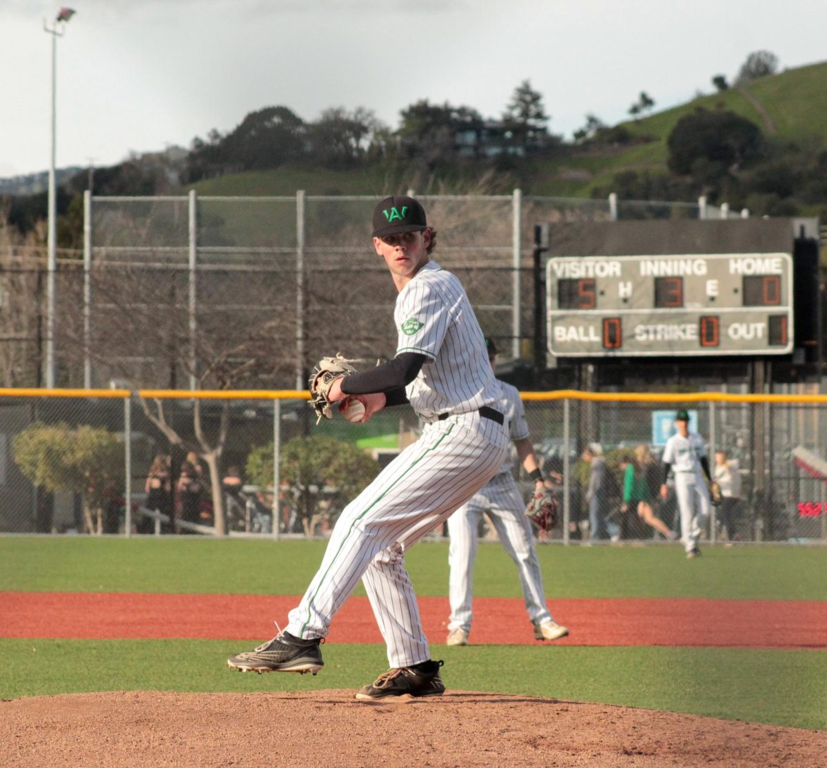 Boys varsity baseball player senior Leo Hendriks rears back to deliver a pitch.