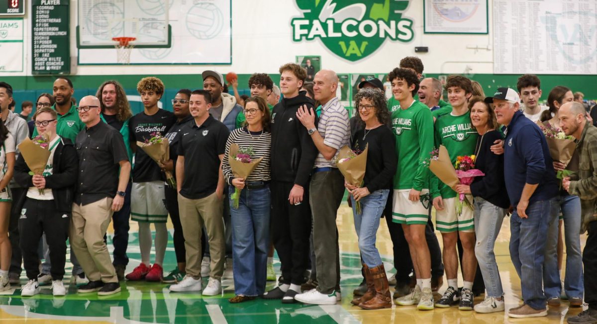Seniors stand with their families and coaches to pose for a photo.
