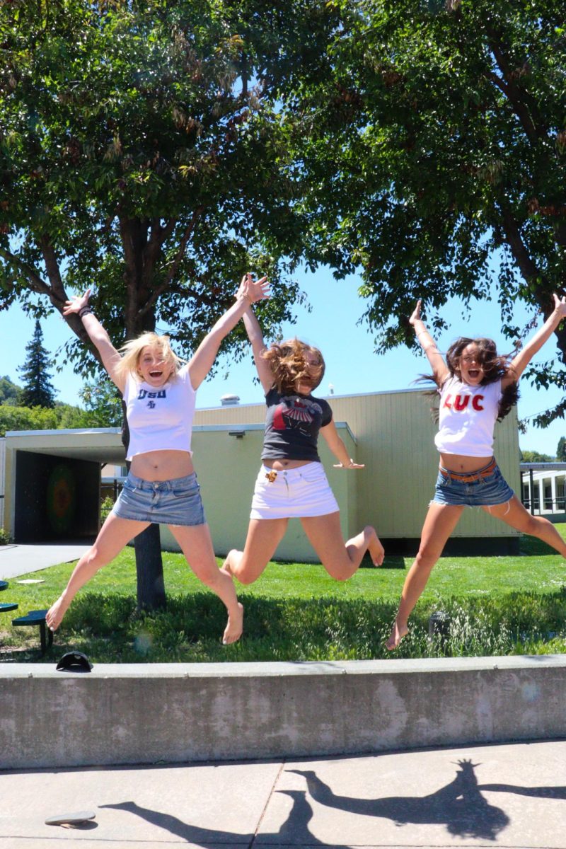 Seniors Miya Hermans (left), Evelyn Jones (middle) and Delphina Dong (right) jump with excitement in their college gear. 
