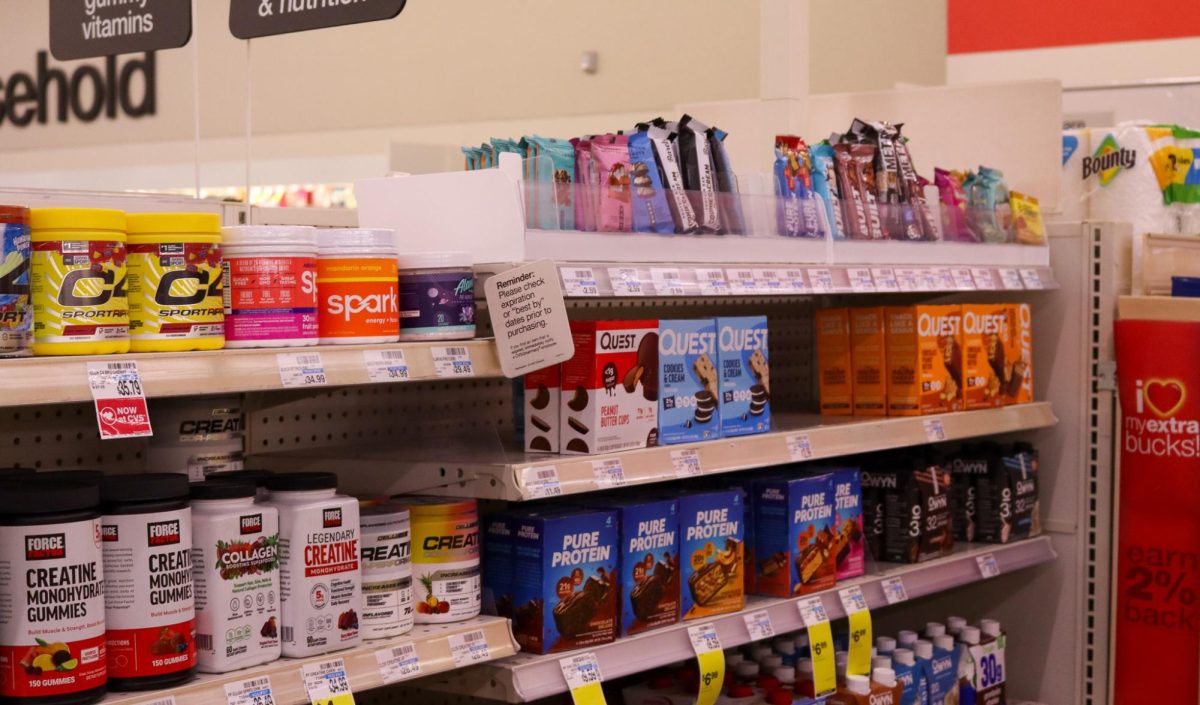Protein supplements and snacks line shelves inside a CVS section. 
